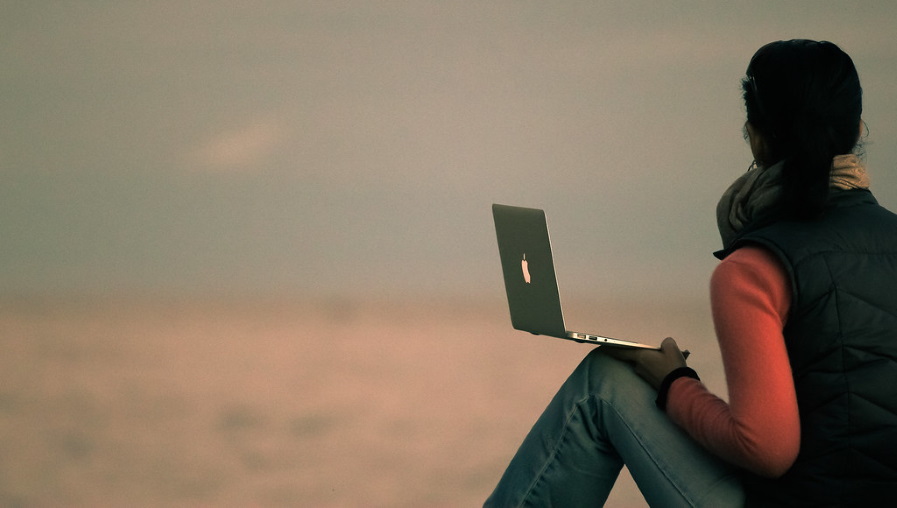 A woman gets a telehealth session while sitting in the wilderness.